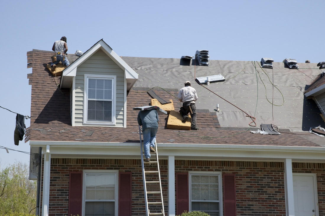 Professional roofers working on a house roof replacement project